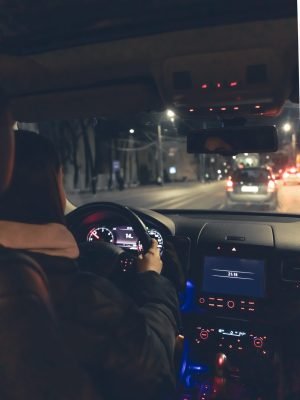 A young woman driving her modern car at night in the city. Night road, view from the car interior.